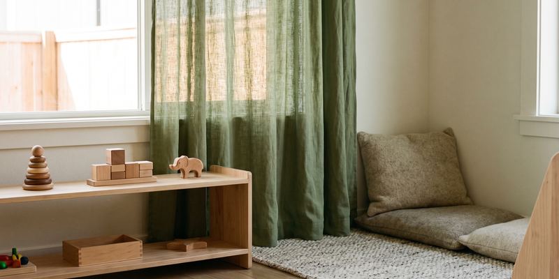 Ruhige Ecke in einem Kitaraum mit niedrigem Holzregal, wenigen Spielsachen und einer Kuschelecke